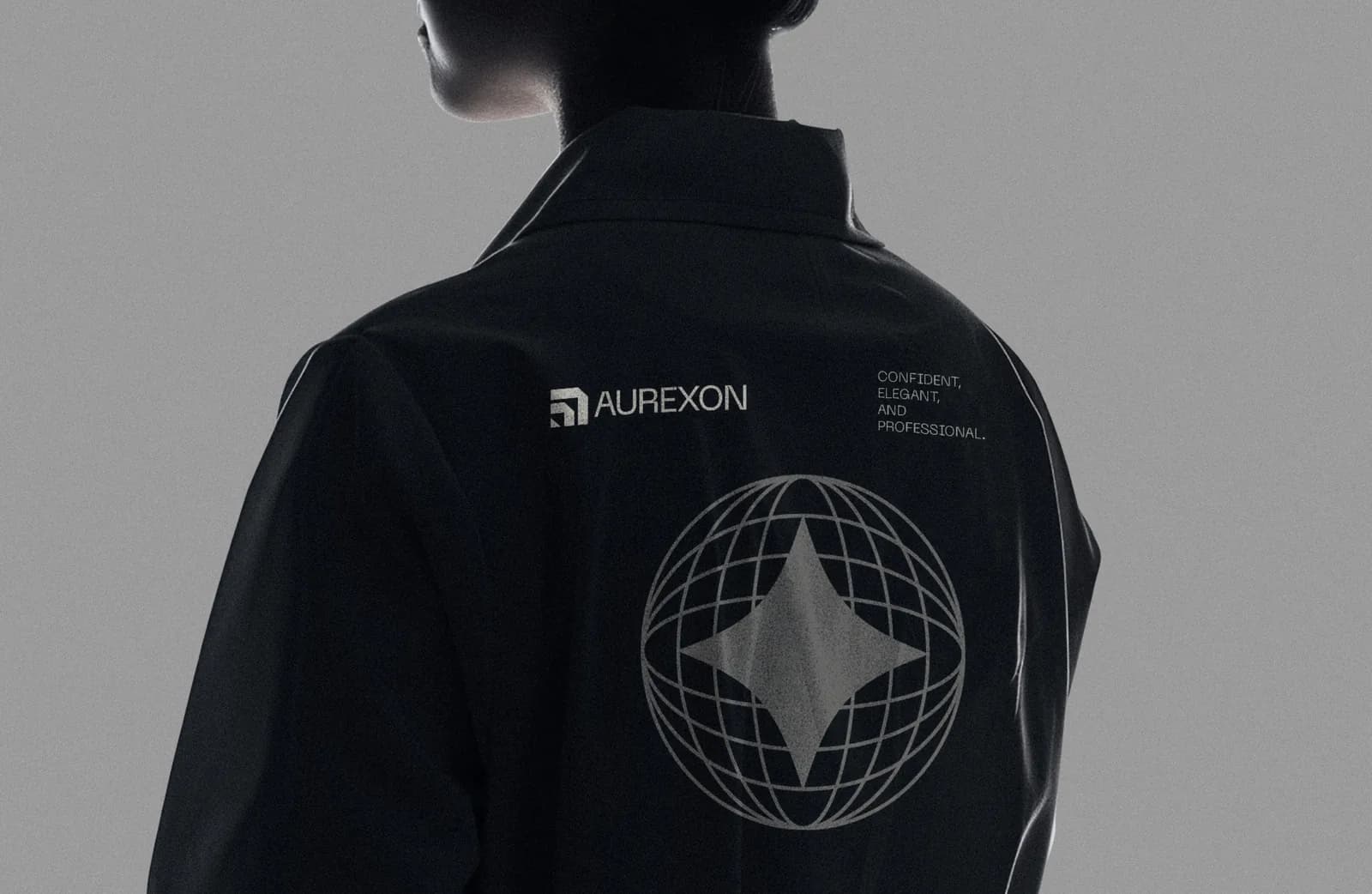 The back of a black Aurexon work jacket with the small symbol and wordmark across the shoulders, the words Confident, elegant and professional, and a large globe-and-star graphic printed below.